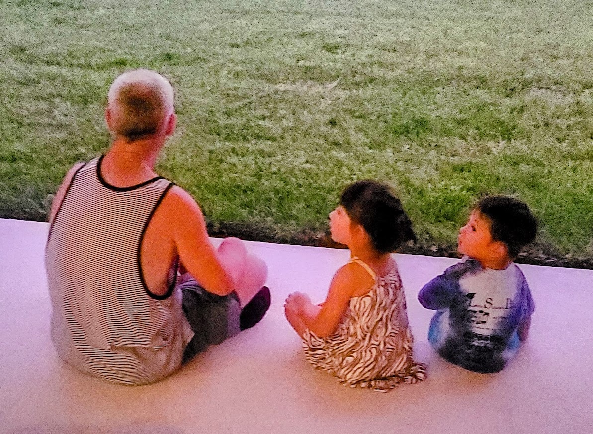 A grandfather sitting with two young children on the porch — multigenerational connection at Porchaven™