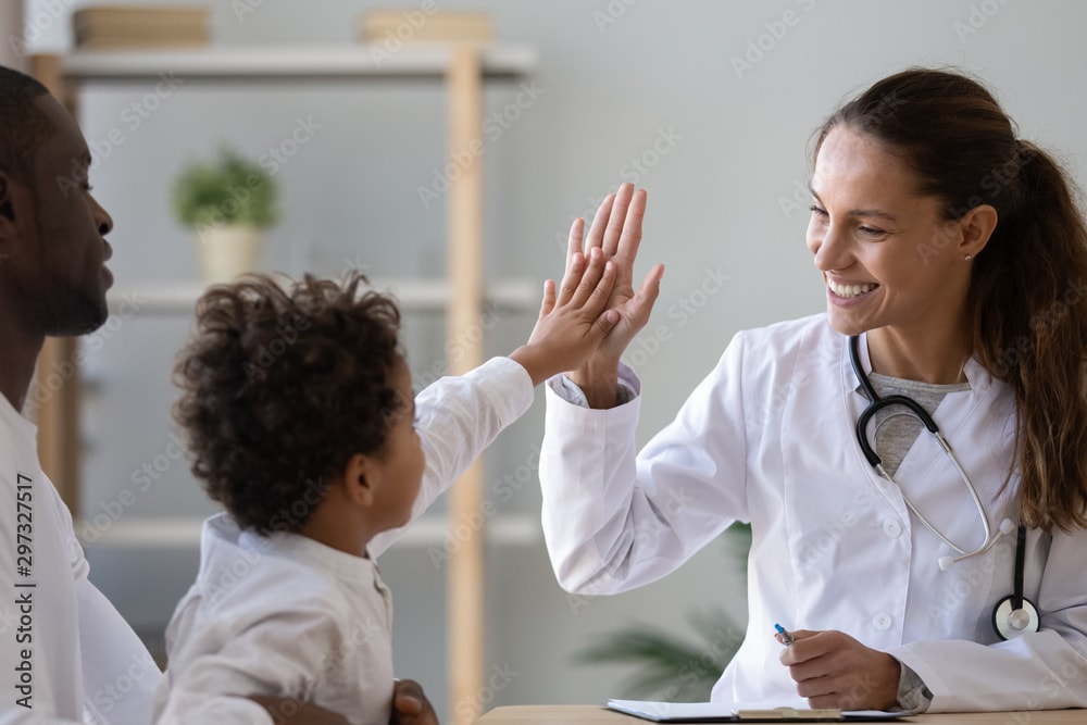 Pediatrician giving a high-five to a young child — trusted healthcare providers